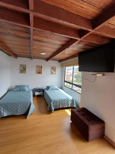 a bedroom with two beds and a flat screen tv at Casa Café & Orquídea - Hospedaje in Bogotá