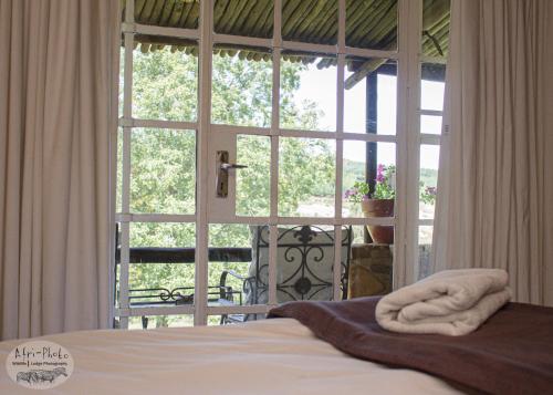 a bedroom with a large window with a bed in front at Gunyatoo Trout Trout Farm & Guest Lodge in Sabie