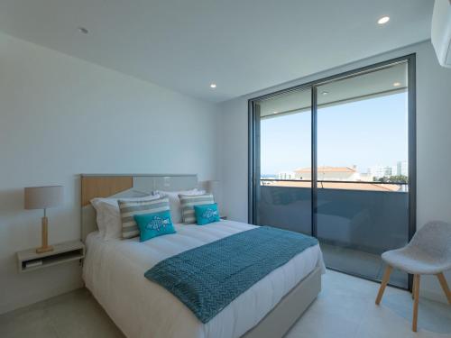 a bedroom with a bed and a large window at Sea View Apartment in Santo Amaro