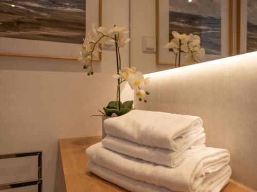 a stack of towels on a table with a vase of flowers at Sea View Apartment in Santo Amaro