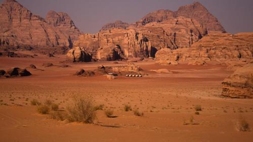 a view of the desert with mountains and a camel caravan at Wadi Rum Camp &Tours in Wadi Rum
