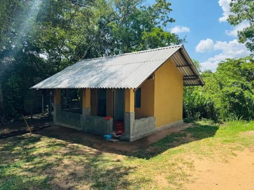 una pequeña casa amarilla con techo de metal en Thalpathwewa Cave Temple, 