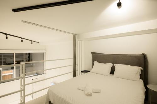 una camera da letto con un letto con lenzuola bianche e una finestra di South Metro Loft ad Atene