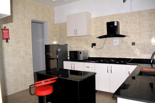 una cucina con mobili bianchi e un piano di lavoro nero di Posh Modern Ikeja 2 Bedroom a Ikeja