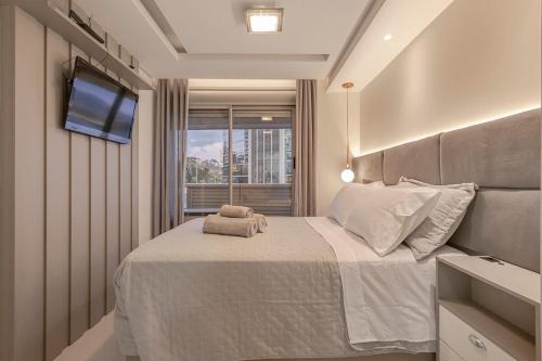 a bedroom with a bed with a tv on the wall at 413 Trend Residence High Standard in Porto Alegre