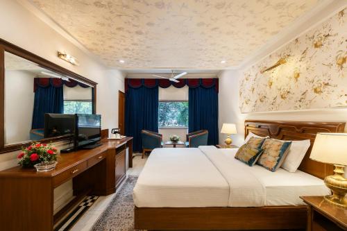 a bedroom with a bed and a desk and a television at Hotel Kwality Regency in Chandīgarh