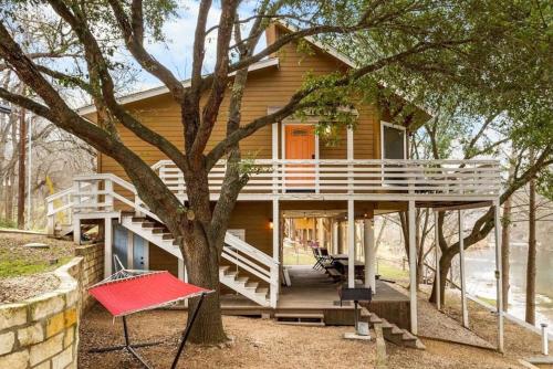 a house with a large porch and a tree at Spacious Cabin Rental Overlooking the Guadalupe River near Austin, Texas in Fourth Crossing