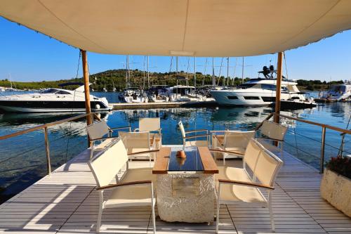 a dock with chairs and a table and boats in the water at Rooms by the sea Cove Golubovac, Kornati - 23062 in Bizikovica