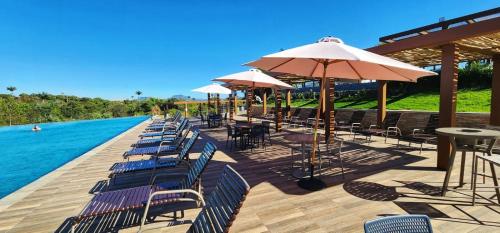 a row of chairs and umbrellas next to a pool at Resort Quinta Santa Barbara in Pirenópolis