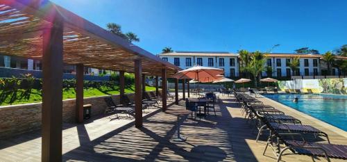 a patio with tables and chairs next to a pool at Resort Quinta Santa Barbara in Pirenópolis
