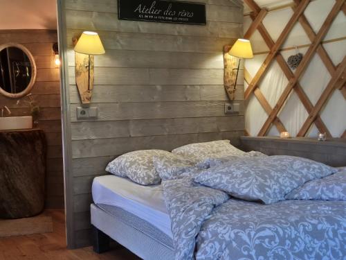 a bedroom with a bed with blue comforter and two pillows at Yourtes l'atelier des rêves Castanea - Séjour nature au cœur du Parc Loire Anjou Touraine in Continvoir
