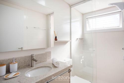 a white bathroom with a sink and a shower at Estúdio em Cond. c/ Pisc. a 550m Praia TOR0407 in Imbituba