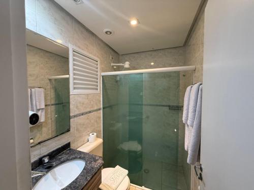ein Badezimmer mit Glasdusche und Waschbecken in der Unterkunft Flat estudio 110 Amarilis Riviera de São Lourenço, 03 piscina climatizada, serviço de hotelaria, limpesa e troca de toalhas diária, carregador veiculo elétrico e servico de praia finais de semana WiFi 500 in Riviera de São Lourenço