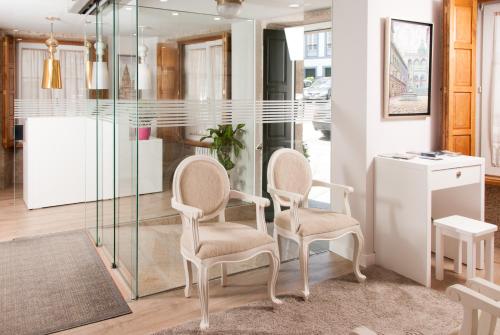 2 sillas en una habitación con pared de cristal en Linares Rooms Santiago, en Santiago de Compostela