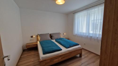 a bedroom with a bed with blue sheets and a window at Appartements Stadler in Breitenbrunn
