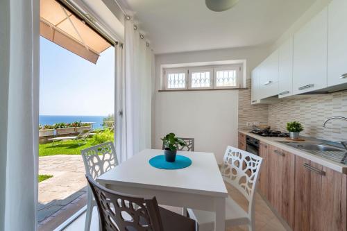 een keuken met een tafel en stoelen en uitzicht op de oceaan bij Villa Marilena in Marina di Casalvelino