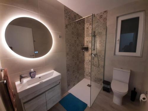 een badkamer met een toilet, een wastafel en een spiegel bij Sunsets Duplex Penthouse Gozo in Kerċem