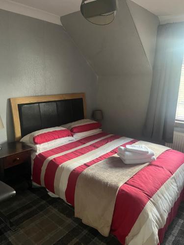 een slaapkamer met een groot bed met rode en witte lakens bij Rowan in Bellshill
