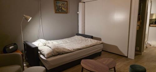 a small bed in a room with chairs and a lamp at Aurora river cabin in Kiruna