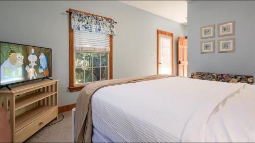 a bedroom with a bed and a flat screen tv at Thurston House Inn in Ocracoke