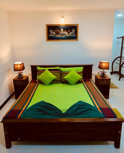 a large bed with green sheets and two lamps at Sigiri Prabha Villa in Sigiriya