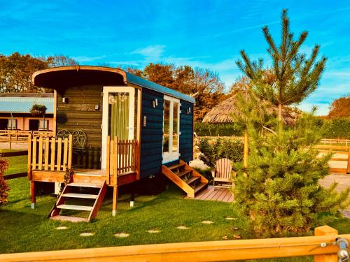 a blue tiny house with a porch and a deck at Magnolia Hoeve - Unieke Bestemming voor Paardenliefhebbers en Bijzondere Overnachtingen in de natuur in Ledeacker