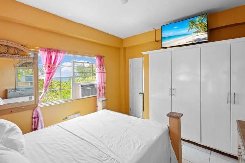 Un dormitorio con una cama y un televisor en una pared. en Oceanview • Mins to the Beach • Private BR Balcony, en Moule à Chique
