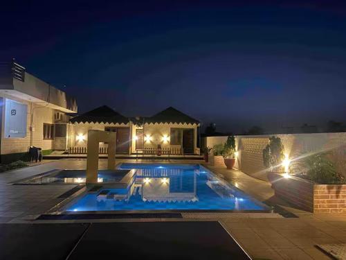 a swimming pool in front of a house at night at The Starlight Farmstay- Poolside Tent Stay in Jaipur in Jāmb
