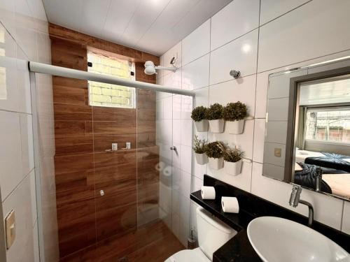 a bathroom with a toilet and a sink and a mirror at Marmeu Pitangueiras in Guarujá