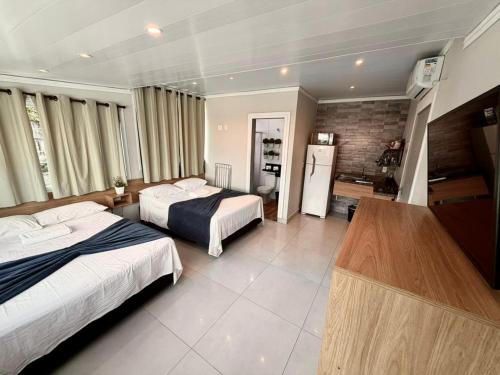 a hotel room with two beds and a refrigerator at Marmeu Pitangueiras in Guarujá