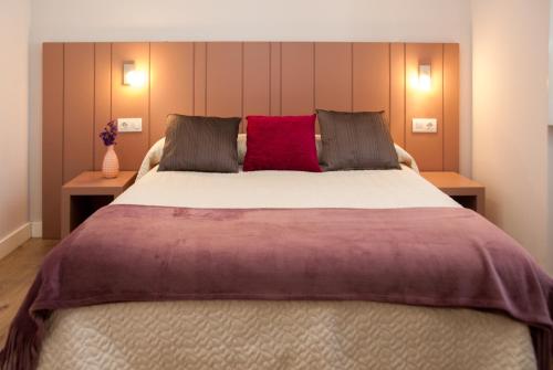 a bedroom with a large bed with a red pillow at Linares Rooms Santiago in Santiago de Compostela