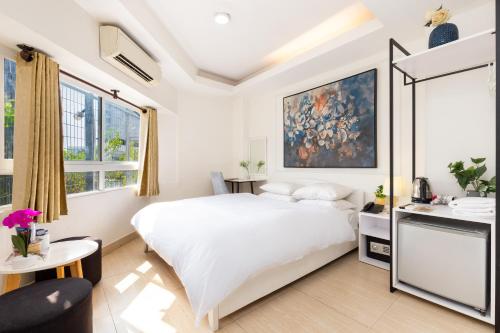 a white bedroom with a large bed and a table at Boutique Passion Hotel in Ho Chi Minh City