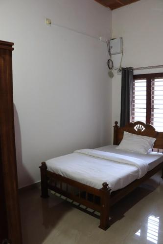 a bedroom with a bed with white sheets and a window at Perya Hills in Periya