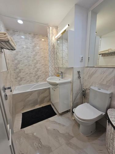 a bathroom with a toilet and a tub and a sink at White Central Apartment in Bistriţa
