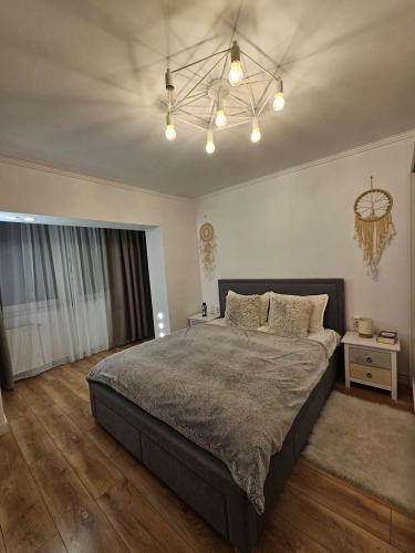 a bedroom with a large bed and a chandelier at White Central Apartment in Bistriţa