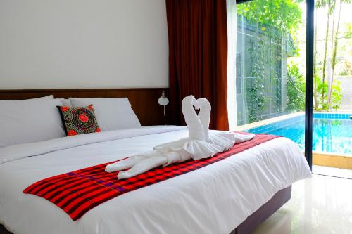a bed with a swan on a red and white towel at The Umbrella House - SHA Extra Plus in Kamala Beach