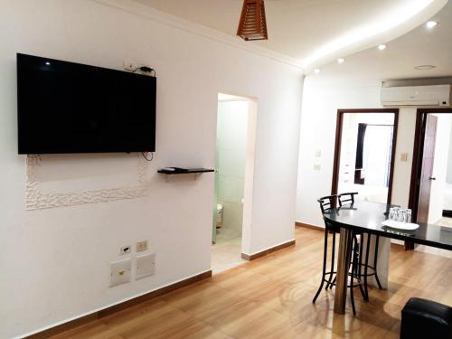 a living room with a table and a television on a wall at Hotel Adulam in Santa Cruz de la Sierra
