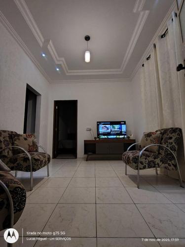 a living room with two chairs and a television at LM Home 1 - casa com 2 quartos in Governador Valadares