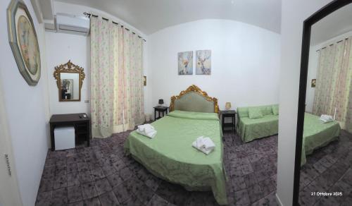 1 dormitorio con 2 camas verdes y espejo en B&B Domus Morfeo, en Santa Maria Capua Vetere