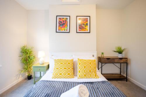 ein Schlafzimmer mit einem Bett mit gelben und blauen Kissen in der Unterkunft Modern 2 BR Apt with Free parking in Cardiff Pontcanna in Cardiff