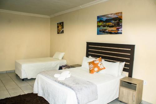 a hotel room with two beds with white sheets at Stopover lodge in Rustenburg