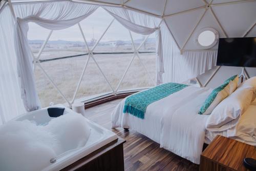 a room with a tub and a bed and a window at Enxe Glamping & Spa 