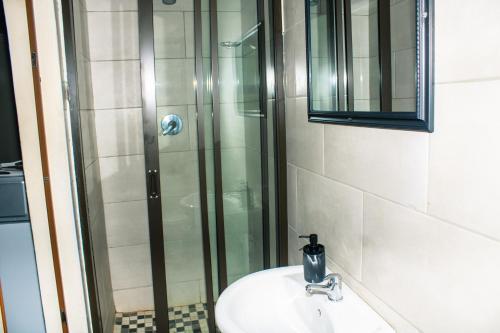 a bathroom with a glass shower and a sink at Stopover lodge in Rustenburg