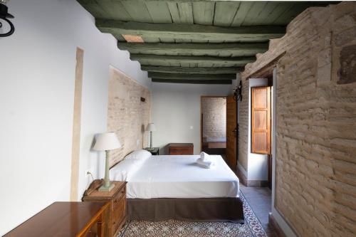 a bedroom with a white bed and a stone wall at Hospedería Monasterio de San Leandro in Seville