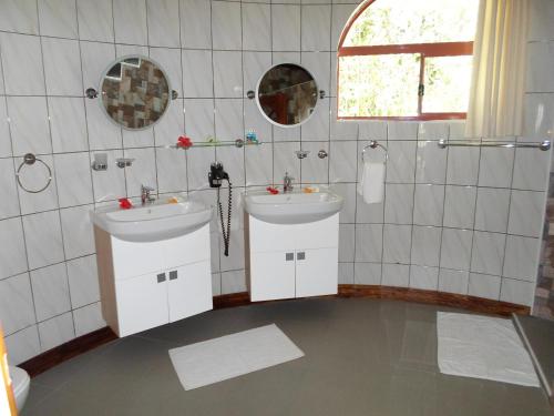 La salle de bains est pourvue de 2 lavabos et de 2 miroirs. dans l'établissement Amitie Chalets Praslin, à Grand Anse