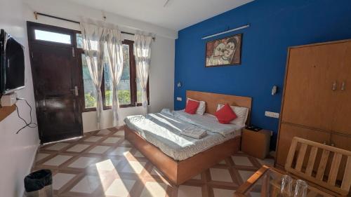 1 dormitorio con paredes azules y 1 cama con almohadas rojas en The Bran Saga, en Haripūr