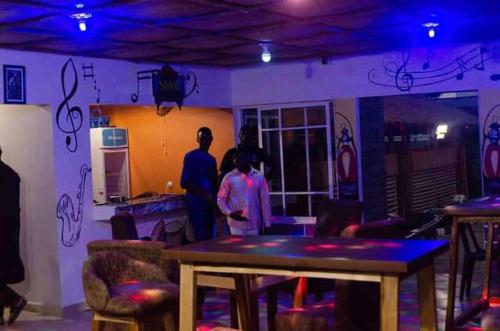 dos personas de pie en una habitación con una mesa en Tracer Wave Cabin, en Akwanga