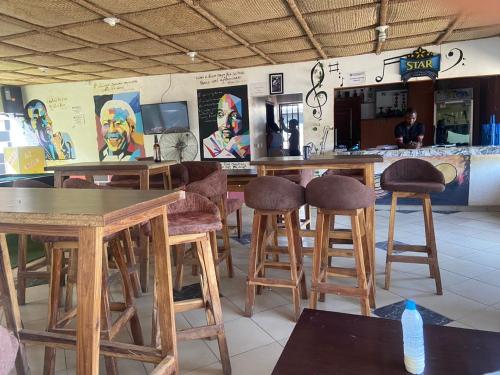 a restaurant with wooden tables and stools in a room at Tracer Wave Cabin in Akwanga
