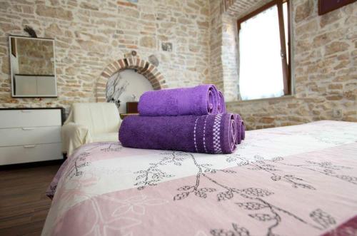 ein lila Kissen auf einem Bett in der Unterkunft Traditionelles Steinhaus mit Innenhof und Terrasse im Zentrum von Medulin, nicht weit vom Strand entfernt in Medulin