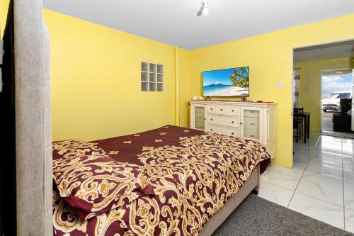 een slaapkamer met een bed, een dressoir en een tv bij Mins from Beach • WiFi + AC • BBQ Grill in Vieux Fort